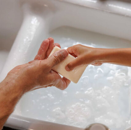 Dr. Bronner's bar soap passed between hands over bath