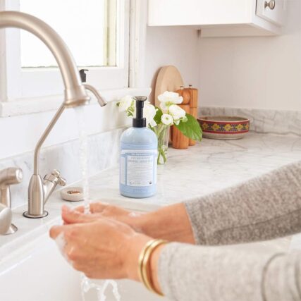 Washing hands in sink with Dr Bronners Baby unscented Organic Sugar Pump Soap in Background