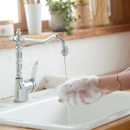 Person washing hands with soap lather in bathroom sink