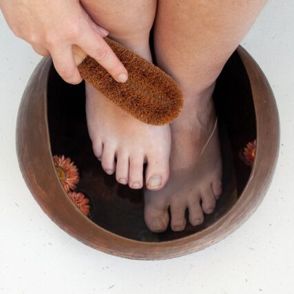 Ecomax foot brush scrubbing feet in ceramic bowl of water