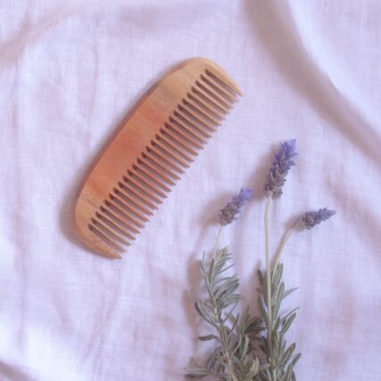 Ecomax neem wood comb on white cloth with flowers